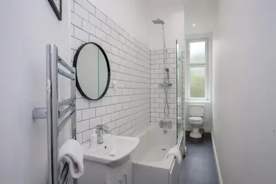 a bathroom with a sink and a tub and a mirror at Modern, Light-filled and Sleek West End Apartment in Glasgow