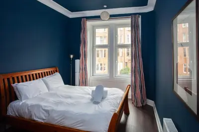 a bedroom with a bed with a stuffed animal on it at Modern, Light-filled and Sleek West End Apartment in Glasgow