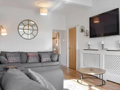 a living room with a gray couch and a flat screen tv at Loanmhor in Kilmory