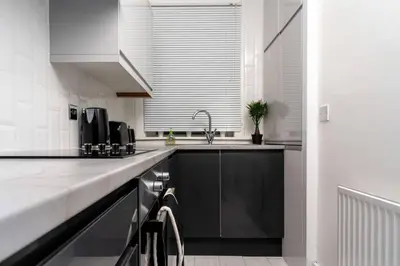 a kitchen with a sink and a counter top at Cheerful 2 Bedroom Homely Apartment, Sleeps 4 Guest Comfy, 1x Double Bed, 2x Single Beds, Free Parking, Free WiFi, Suitable For Business, Leisure Guest, Contractors, QE Hospital, Glasgow, Near Airport & City Centre, Perfect For Common Wealth Games 2026 in Glasgow