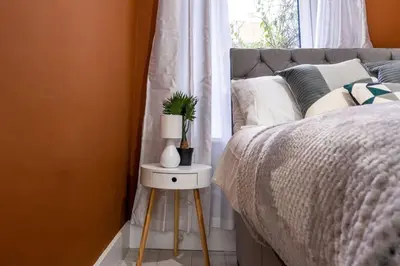 a bed with a plant on a night stand next to a window at Cheerful 2 Bedroom Homely Apartment, Sleeps 4 Guest Comfy, 1x Double Bed, 2x Single Beds, Free Parking, Free WiFi, Suitable For Business, Leisure Guest, Contractors, QE Hospital, Glasgow, Near Airport & City Centre, Perfect For Common Wealth Games 2026 in Glasgow