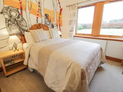 a bedroom with a large bed and a window at Torview House in Peebles