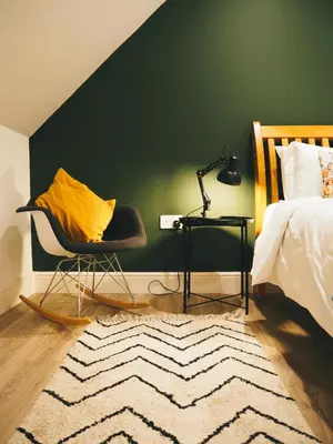a bedroom with a green wall and a chair and a bed at The Trossachs Collection in Kepculloch