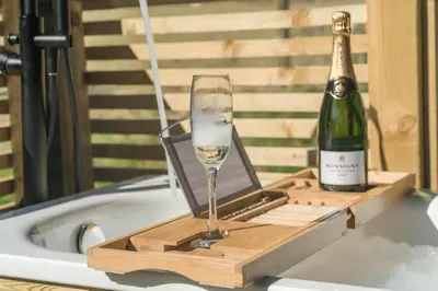 a bottle of champagne and a wine glass in a bath tub at The Trossachs Collection in Kepculloch