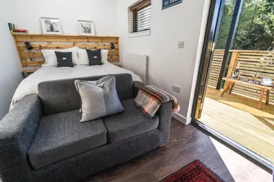 a bedroom with a bed and a couch with pillows at The Trossachs Collection in Kepculloch