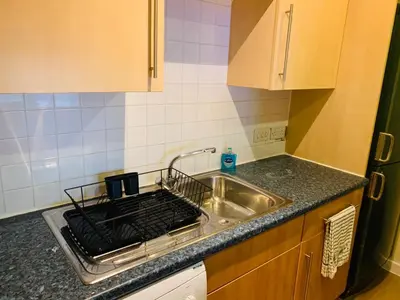 a kitchen counter with a sink and a stove at Modern 2 Bed Apartment, Close to Gla Airport & M8 in Paisley