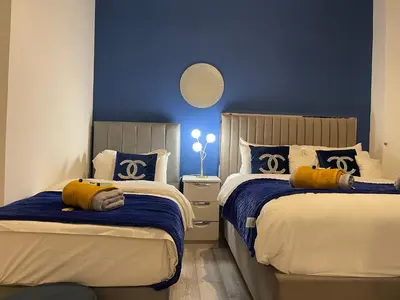 a bedroom with two beds and a blue wall at HLA Holytown in Mossend