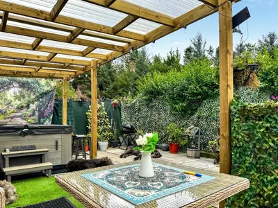 a patio with a table and a wooden pergola at Bumbles Barn in Slamannan