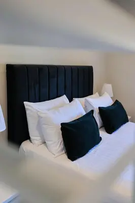 a bed with black and white pillows on it at The White City Apartment in Oban