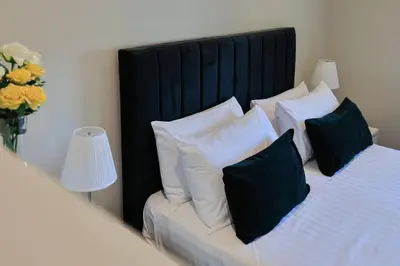 a bedroom with a bed with a black headboard and pillows at The White City Apartment in Oban