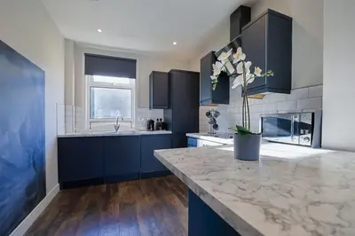a kitchen with blue cabinets and a marble counter top at The White City Apartment in Oban