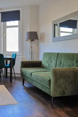 a living room with a green couch and a table at The White City Apartment in Oban