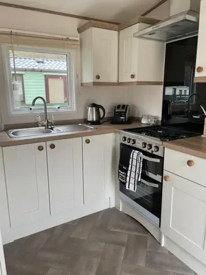 a kitchen with white cabinets and a sink and a stove at The Wimbledon 70 in Dunoon