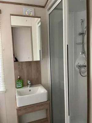a bathroom with a sink and a mirror and a shower at The Wimbledon 70 in Dunoon