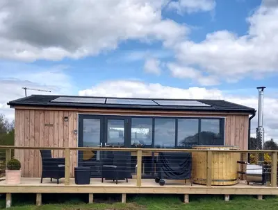 a tiny house with a solar roof on a deck at Cleeves Cabins Ailsa Luxury Lodge with hot tub in Dalry