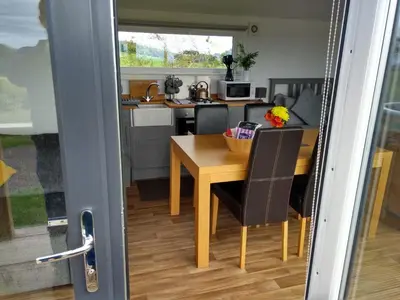 a small kitchen with a wooden table and chairs at Cleeves Cabins Ailsa Luxury Lodge with hot tub in Dalry