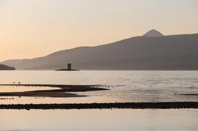 a body of water with a lighthouse in the distance at MacKintosh in Pitlochry