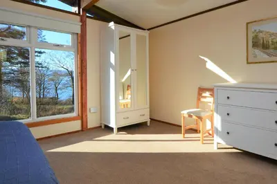 a bedroom with a bed and a dresser and a window at Musselshell Lodge in Otter Ferry