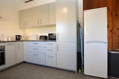 a kitchen with white cabinets and a refrigerator at Musselshell Lodge in Otter Ferry