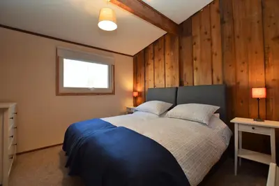 a bedroom with a bed with wooden walls and a window at Scallopshell Lodge in Otter Ferry