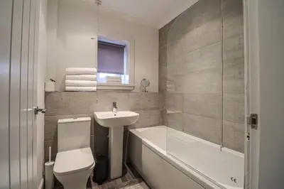 a bathroom with a sink and a toilet and a bath tub at Townend Apartment in Dumbarton