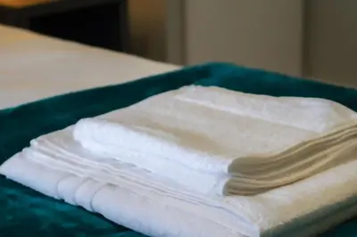 a stack of white towels sitting on a bed at Townend Apartment in Dumbarton