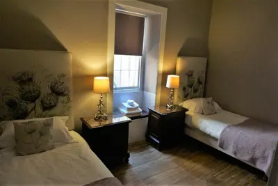 two beds in a room with two lamps and a window at Old Town 163 in Edinburgh