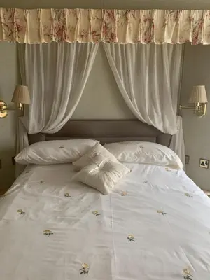 a white bed with white curtains and pillows on it at The Monaco 32 in Dunoon