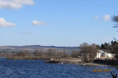 a large body of water with a house in the background at Craiglynn Holiday Apartment Loch Lomond in Balloch