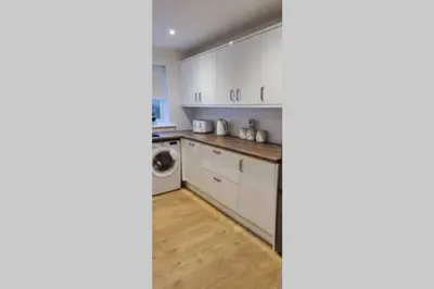 a kitchen with white cabinets and a washer and dryer at Craiglynn Holiday Apartment Loch Lomond in Balloch