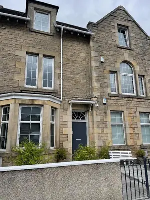 a brick house with a blue door and windows at Premier Apartment C in Broxburn