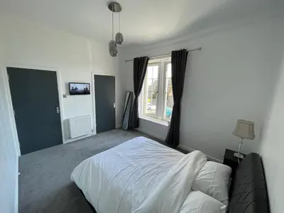 a bedroom with a white bed and a window at Premier Apartment C in Broxburn
