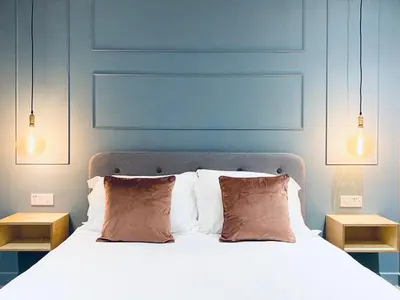 a bedroom with a bed with two night stands and two lights at Lynwood Studio in Oban