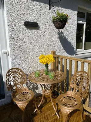 a table with chairs and a vase of flowers on a porch at Lynwood Studio in Oban