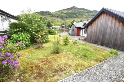 a small yard with flowers and a building at Arivean Cottage in Lochgoilhead