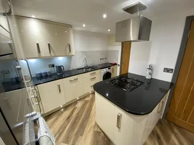 a kitchen with a black counter top and white cabinets at holidayhomemoffat,com (Stable Cottage) in Moffat