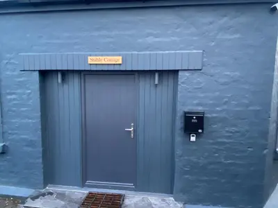 a blue building with a blue door with a sign on it at holidayhomemoffat,com (Stable Cottage) in Moffat