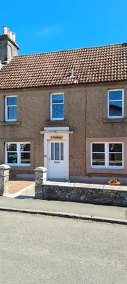a brick house with a white door on a street at ALLARDYCE in Kincardine