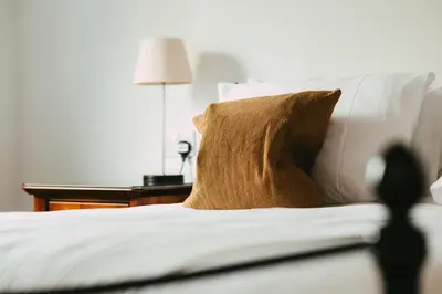 a brown pillow on a white bed with a table at Ardeonaig Hotel & Restaurant in Ardeonaig