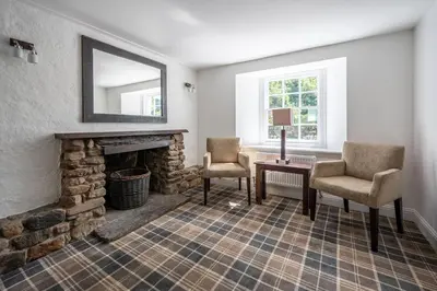 a living room with a fireplace and two chairs at Ardeonaig Hotel & Restaurant in Ardeonaig