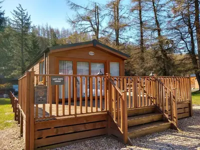 a small cabin with a staircase and a fence at Lazy Days Lodge, Glendevon, Perthshire in Glendevon
