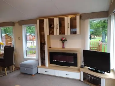 a living room with a tv and a entertainment center at Lazy Days Lodge, Glendevon, Perthshire in Glendevon