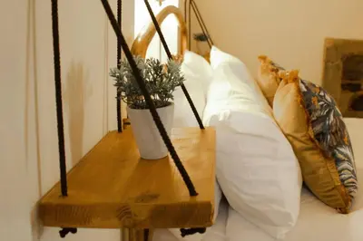 a bunch of pillows sitting on a bed with a table at The Old Jail Apartment, Inveraray in Inveraray