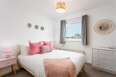 a bedroom with a bed with pink pillows and a window at Walker Suite No52 - Donnini Apartments in Kilmarnock