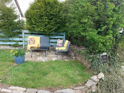 two chairs and a table in a yard with a hedge at THE BOTHY SUITE BY TEMPLE WOOD in Lochgilphead