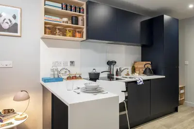 a kitchen with black cabinets and white countertops at Silk Mill Edinburgh in Edinburgh