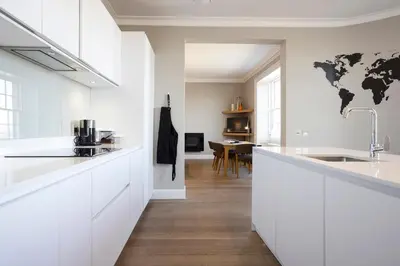 a white kitchen with a world map on the wall at JOIVY Splendid Apartment in New Town in Edinburgh