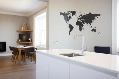 a kitchen with a white counter and a world map on the wall at JOIVY Splendid Apartment in New Town in Edinburgh