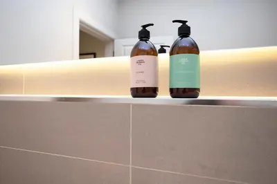 two bottles of soap sitting on a shelf in a bathroom at JOIVY Splendid Apartment in New Town in Edinburgh