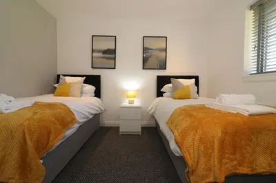 two beds in a room with a lamp on a table at Signature - Railway House 5 bed in Maryhill